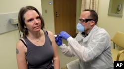 Seorang petugas medis memberikan suntikan pertama vaksin kepada Jennifer Haller (kiri), dalam uji klinis tahap pertama vaksin virus corona COVID-19, di Kaiser Permanente Washington Health Research Institute in Seattle, 16 Maret 2020. (Foto: AP)