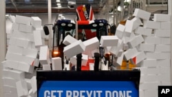 Britain's Prime Minister Boris Johnson drives a JCB through a symbolic wall with the Conservative Party slogan 'Get Brexit Done' in the digger bucket, during an election campaign event at the JCB manufacturing facility in Uttoxeter, England.