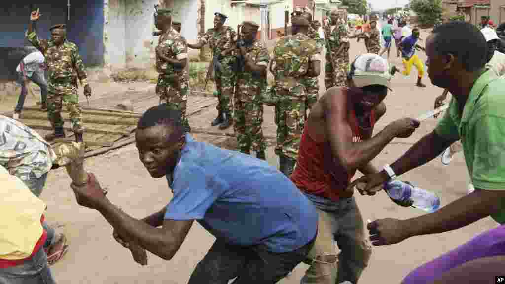 Des soldats tirent en l'air pour disperser des manifestants qui ont acculé Jean Claude Niyonzima un membre présumé de la milice Imbonerakure de la jeunesse du parti au pouvoir dans un égout dans le quartier de Cibitoke de Bujumbura, au Burundi, jeudi 7 mai 2015.