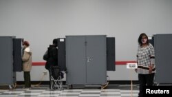 An early voter wearing a protective face mask waits to cast her vote in two runoff elections that will determine control of the U.S. Senate, in Atlanta, Dec. 4, 2020. 