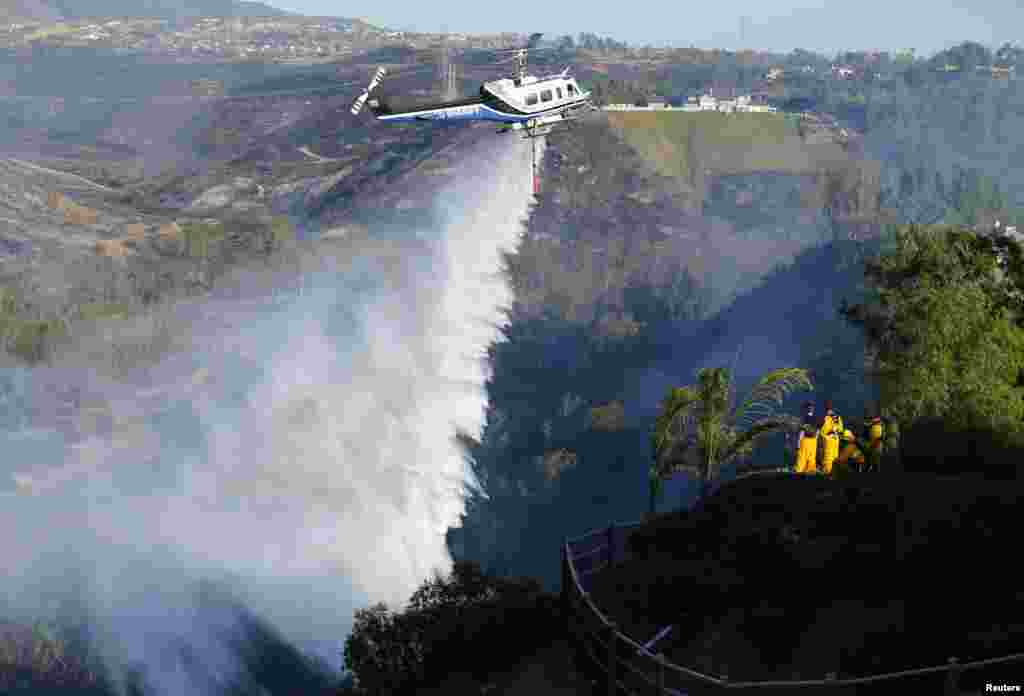 Helikopter menjatuhkan air untuk memadamkan kebakaran di sebuah bukit di kota Bernardo, utara kota San Diego, California, AS.