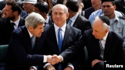 Presiden srael Shimon Peres berjabat tangan dengan Menlu AS John Kerry, sementara PM Netanyahu duduk diantara mereka saat upacara peringatan peristiwa Holocaust di Yad Vashem, Yerusalem (8/4).