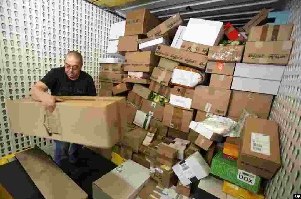 An employee of DHL, a division of German postal service Deutsche Post, unloads parcels from a transport vehicle at the company's logistics center in Gross Schwass near Rostock. During the pre-Christmas period, around 12,000 parcels per day are handled at the center, which is the double the usual amount, Dec. 18, 2013.