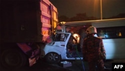 Para petugas dari Dinas Pemadam Kebakaran dan SAR Malaysia sedang bekerja di lokasi kecelakaan lalu lintas yang menewaskan seorang supir dan mencederai empat pebulu tangkis, termasuk pebulu tangkis nomor satu dunia, Kento Momota, di jalan tol menuju Banda