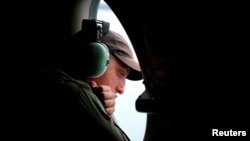 Awak pesawat AP-3C Orion milik Angkatan Udara Australia melongok keluar jendela dalam pencarian pesawat Malaysia Airlines Flight MH370 yang hilang di atas Samudera Hindia bagian selatan (26/3).
