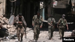 Para tentara Pasukan Demokratik Suriah (SDF) berjalan melintasi puing-puing bangunan dan toko-toko yang hancur di Kota Manbij, Wilayah Aleppo, Suriah, 10 Agustus 2016.