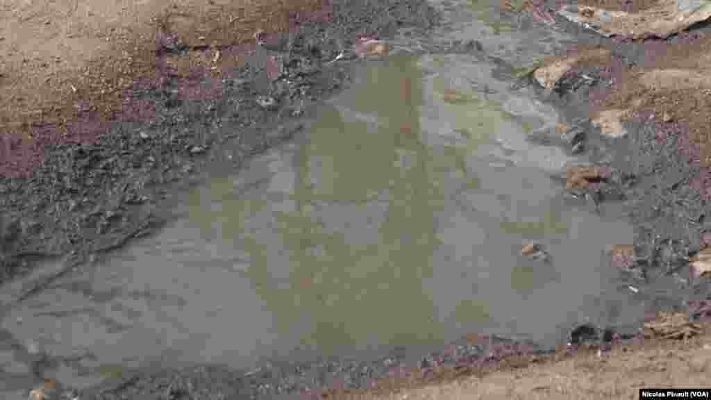 Dirty water is seen in puddles at the New Kuchogoro camp in Abuja, Nigeria, March 7, 2016. (N. Pinault / VOA) 