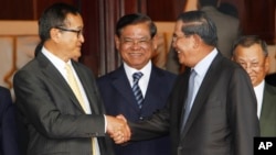 Cambodian Prime Minister Hun Sen, second from right, shakes hands with the main opposition party leader Sam Rainsy, left, of Cambodia National Rescue Party, as Deputy Prime Minister Sar Kheng, second from left, looks on after a meeting in the Senate headquarter, Phnom Penh, Cambodia, file photo. 