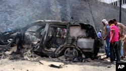 Yemenis inspect the scene of a car bomb attack that killed a Yemeni senior official in the southern port city of Aden, Yemen, Sunday, Dec. 6, 2015.