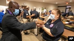 El sacerdote Don Ajoko, unge las manos de Cheryl Blackburn, de Jacksonville, Florida, quien llegó con casi tres docenas de trabajadores de la salud de todo el país para ayudar a complementar el personal del Centro Médico Regional Our Lady of the Lake
