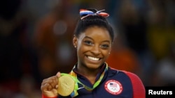 FILE - US gymnyst Simone Biles poses with her gold medal for artistic gymnastics during the victory ceremony at the Rio Olympic Arena in Rio de Janeiro, Brazil, Aug. 16, 2016.