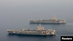 FILE - The U.S. Navy aircraft carrier USS Carl Vinson (CVN 70), bottom, is seen relieving the USS George H.W. Bush in the Arabian Gulf, Oct. 18, 2014. 