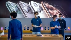 Empleados de una tienda Apple en China usan mascarillas para atender a los clientes. Las fábricas de iPhone en China van retrasadas lo cual desestabiliza los planes de Apple. (Foto Reuters)