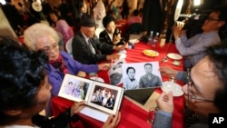Anggota keluarga dari Korsel dan Korut saling memperlihatkan foto keluarga mereka dalam reuni keluarga yang terpisah karena perang di Diamond Mountain resort, Korea Utara, 24 Oktober 2015. (Foto: dok).