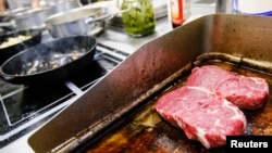 Steaks are being prepared on a grill in the 'Auf da Muehle' restaurant in the western Austrian village of Soell June 2, 2013. 