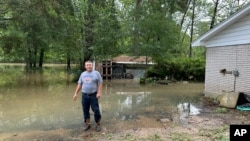 Miguel Flores se encuentra en su patio trasero inundado afuera de su casa en el vecindario de Kingwood, en el noreste de Houston, Texas, EEUU, el sábado 4 de mayo de 2024. (Foto AP/Juan Lozano)