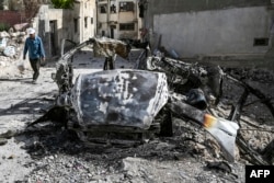 Seorang pria Palestina berjalan melewati kendaraan yang hancur di Jenin setelah serangan pasukan Israel di kota Tepi Barat yang diduduki pada 23 Mei 2024. (Foto: AFP)