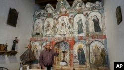 Master santero Felix Lopez speaks during an interview while standing in front of the 1810s 'reredo' or altarpiece he cleaned and preserved in the Holy Rosary Mission Church in Truchas, New Mexico, April 16, 2023.