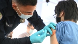 En esta foto de archivo tomada el 23 de agosto de 2021, Brandon Rivera, un técnico médico de emergencia del condado de Los Ángeles, le da una segunda dosis de la vacuna Pfizer-BioNTech Covid-19 a Aaron Delgado, de 16 años.