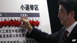 自民党领导人、前首相安倍晋三在当选的议员名字上做记号