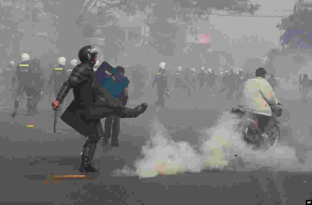 Seorang polisi anti huru hara menghindari granat gas ketika polisi menembakkannya untuk membubarkan demonstran di , 27 Januari 2014.