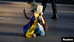 Una joven opositora se sienta para bloquear una calle en Caracas durante las protestas antigubernamentales. 