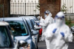 Medical staffers take swabs as they test for COVID-19 at a drive-through, in Rome, Oct. 13, 2020.