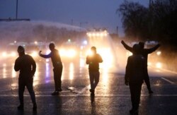 Nationalist youths gesture towards a police line blocking a road near the Peace Wall in West Belfast, Northern Ireland, April 8, 2021.