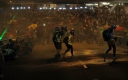 Photographers take cover as police fire water cannon on protesters in Hong Kong, Sept. 28, 2019.