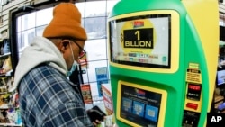 A patron uses the kiosk at a Smoker Friendly store to purchase tickets for the Mega Millions lottery drawing, Jan. 22, 2021, in Cranberry Township, Pa. A player in Michigan bought the winning ticket for the $1.05 billion jackpot.