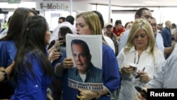 Una mujer sostiene una foto de Manuel Rosales junto a la esposa de Rosales, Eveling Trejo de Rosales, mientras aguardaban su llegada al aeropuerto de Maracaibo, Venezuela, el jueves 15 de octubre de 2015.