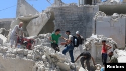 People walk on the rubble of a site hit by a barrel bomb in the rebel held area of Old Aleppo, Syria July 11, 2016. 