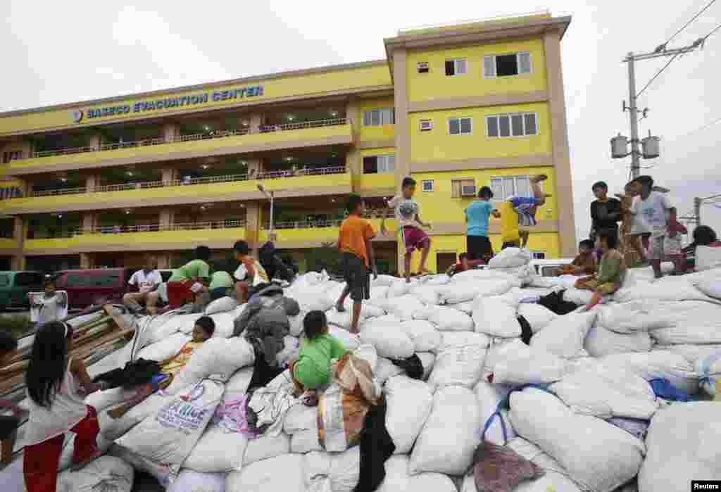 Children play atop sacks of donated clothes at an evacuation center for the coastal community to take shelter from Typhoon Hagupit in Manila, Dec. 8, 2014.