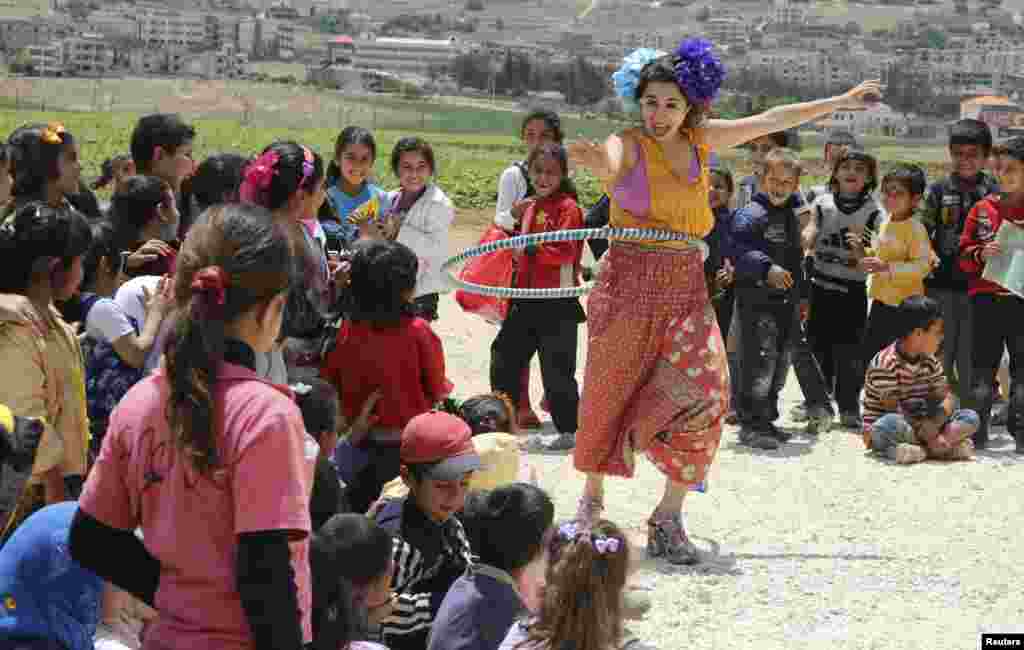 Seorang anggota klub sirkus 'Badut Tanpa Batas' menghibur anak-anak pengungsi Suriah di Jab Janine, Lembah Bekaa barat.