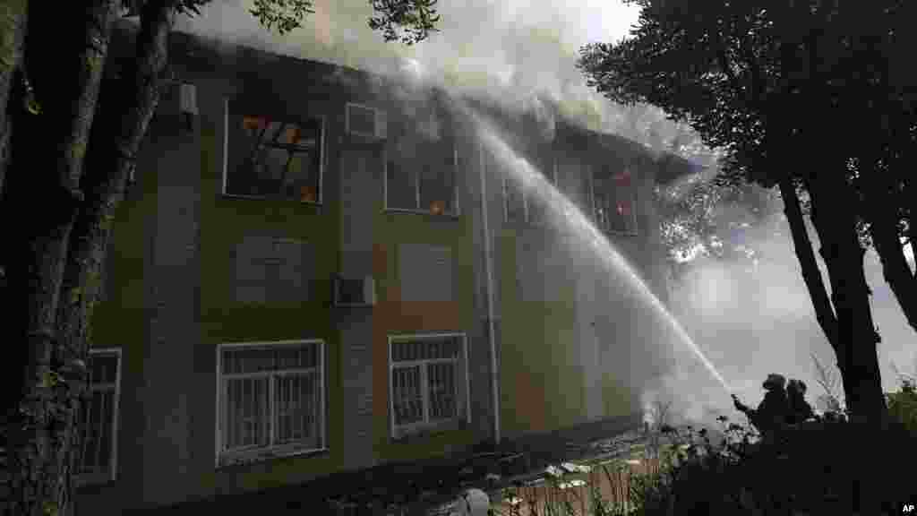 Ukrainian fire fighters put out the fire at the destroyed building after shelling in Donetsk, eastern Ukraine, Aug. 10, 2014.