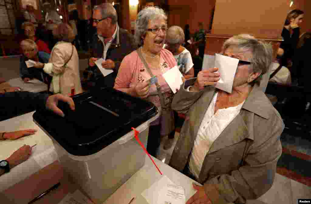A woman kisses a ballot before voting at a polling station for the banned independence referendum in Barcelona, Spain, Oct. 1, 2017.