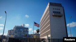 FILE - Tourists in a vintage car pass by the U.S. Embassy in Havana, Cuba, Nov. 7, 2019.