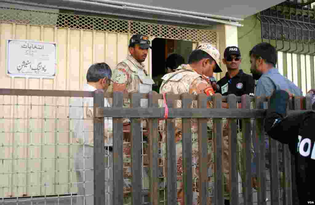رینجرز اور پولیس کے اہلکار ایک ووٹر کا شناختی کارڈ چیک کرتے ہوئے 