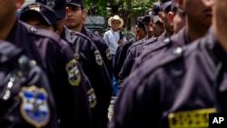 FILE - A man looks at a formation of police and soldiers during a presentation to the press in the Central Square in San Salvador, El Salvador, June 14, 2016 photo.