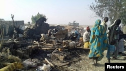 People walk at the site after a bombing attack of an internally displaced persons camp in Rann, Nigeria, Jan. 17, 2017. 