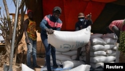 FILE - Workers carry the aid provided by the World Food Program (WFP) for distribution in Pissila, Burkina Faso, January 24, 2020.