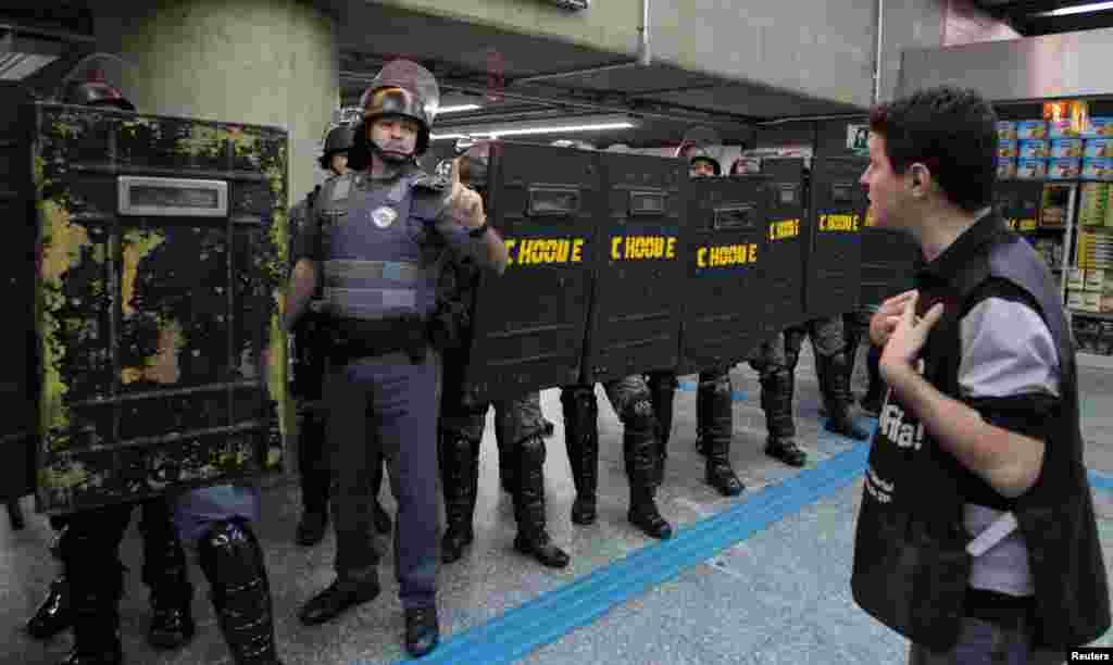 A man stands in front of riot police inside Ana Rosa subway station during the fifth day of metro workers' protest in Sao Paulo, Brazil, June 9, 2014.