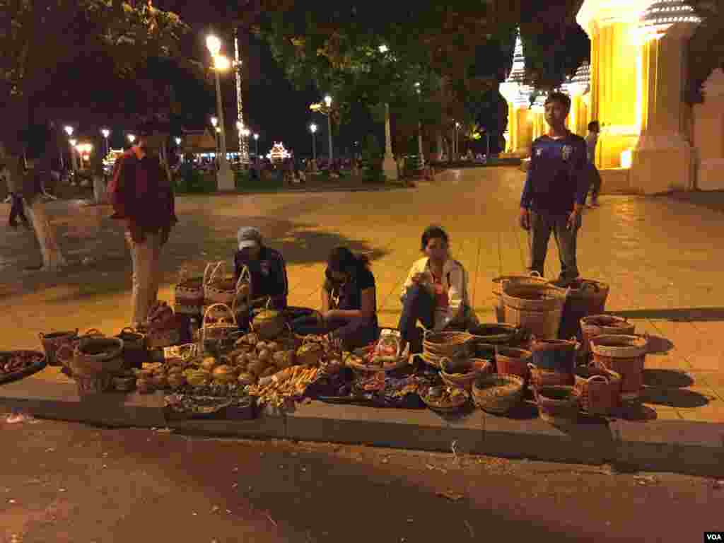 អ្នកលក់នៅមុខព្រះបរមរាជវាំងនៅរាជធានីភ្នំពេញកំពុងរង់ចាំអតិថិជននៅតាមផ្លូវជាប់របស់ព្រះបរមរាជវាំងកាលពីថ្ងៃទី២៦ ខែវិច្ឆិកា ឆ្នាំ២០១៥ ។ (ផន បុប្ផា/VOA)