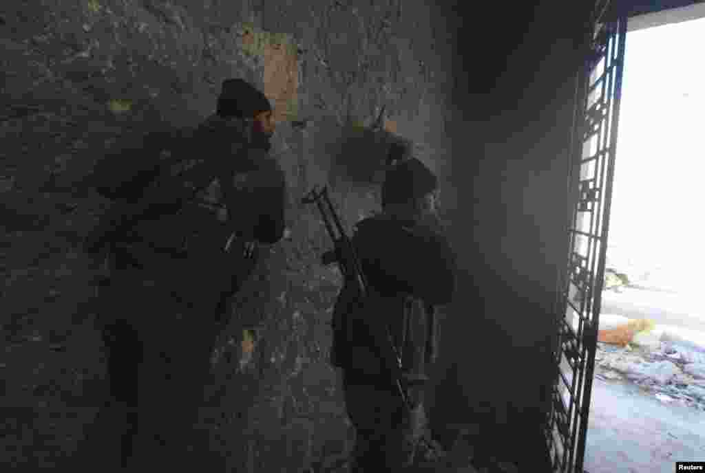 Free Syrian Army fighters take cover during the launch of a homemade rocket towards forces loyal to President Bashar al-Assad near the Justice Palace and the Citadel of Aleppo, Feb. 4, 2014.