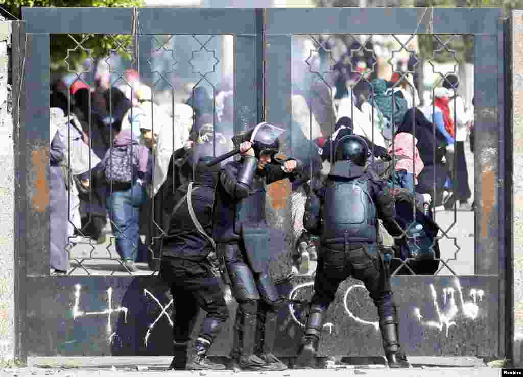 Polisi Mesir berusaha mendobrak pintu masuk di Universitas Al-Azhar, Kairo dalam bentrokan dengan para mahasiwa pendukung kelompok Ikhwanul Muslimin 