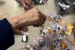 FILE - Workers pack multicolored supplement pills in small resealable bags at an industrial building in Hong Kong, Dec. 1, 2019.