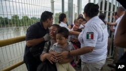 Seorang ibu migran Honduras dan putranya berjalan melalui jembatan setelah melintasi perbatasan antara Guatemala dan Meksiko, di Ciudad Hidalgo, Meksiko, 20 Oktober 2018. (Foto: dok).