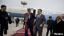 Menlu AS John Kerry (tengah, kiri) disambut oleh Menlu Kyrgizstan Erlan Abdyldaev setibanya di bandara internasional Manas di Bishkek (31/10).