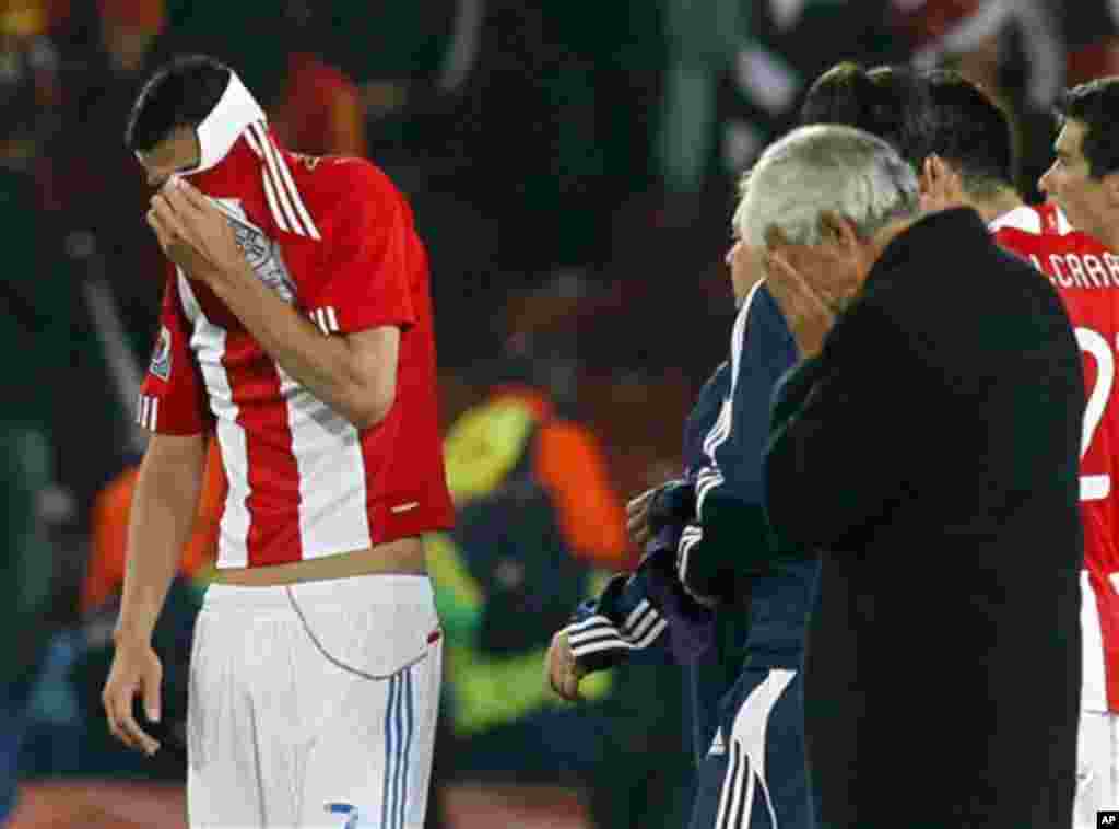 Paraguay's Oscar Cardozo, left, covers his face with his jersey at the end of the World Cup quarterfinal soccer match between Paraguay and Spain at Ellis Park Stadium in Johannesburg, South Africa, Saturday, July 3, 2010. Spain won 1-0 and Cardozo missed