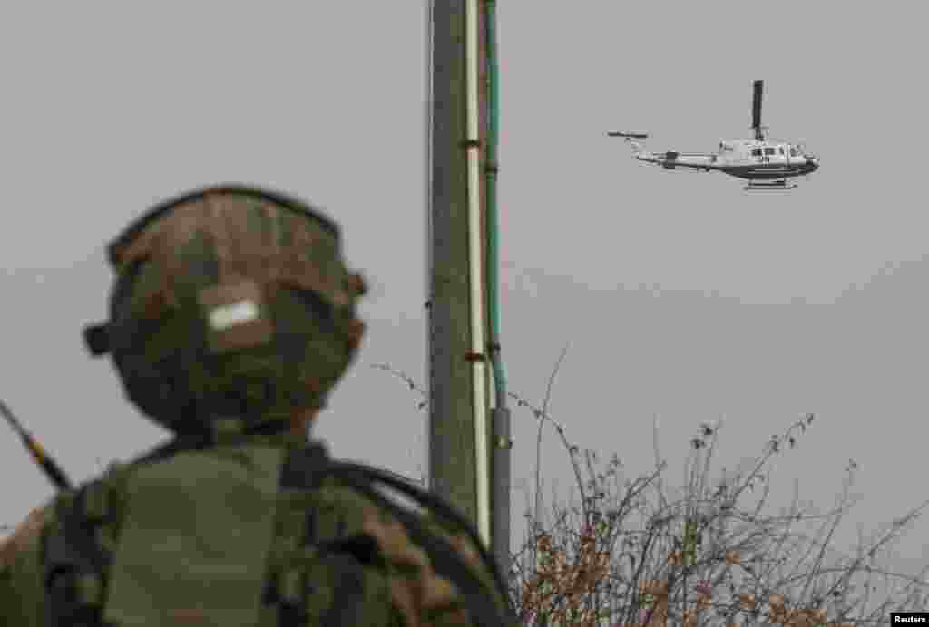An Israeli soldier looks at a U.N. helicopter flying over the Israel-Lebanon border near the northern town of Metula, Israel, Dec. 29, 2013. 